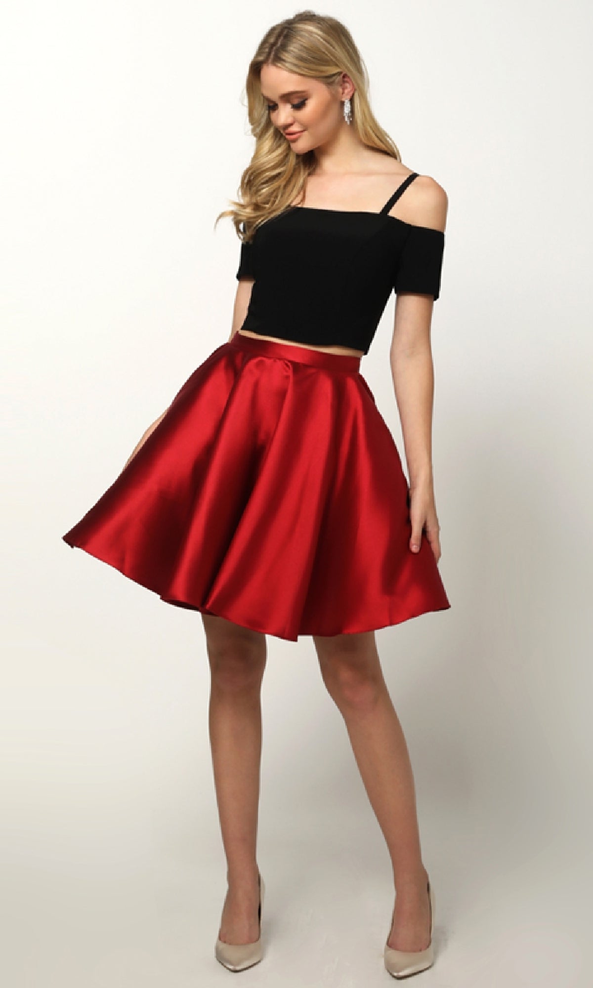A woman models the Juliet 809 Short Party Dress with off-the-shoulder sleeves and a knee-length, a-line skirt, paired with beige high heels, posing against a plain white background.
